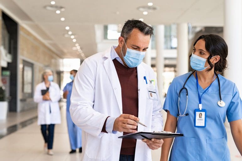 General practitioner and young nurse wearing surgical face masks.